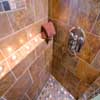 Bathroom Remodel Everett. AFTER: This shower features a shelf running through the shower. The shelf is capped with Travertine floor tile, to tie everything together. The photo also shows Delta shower mixer valve with body jets
